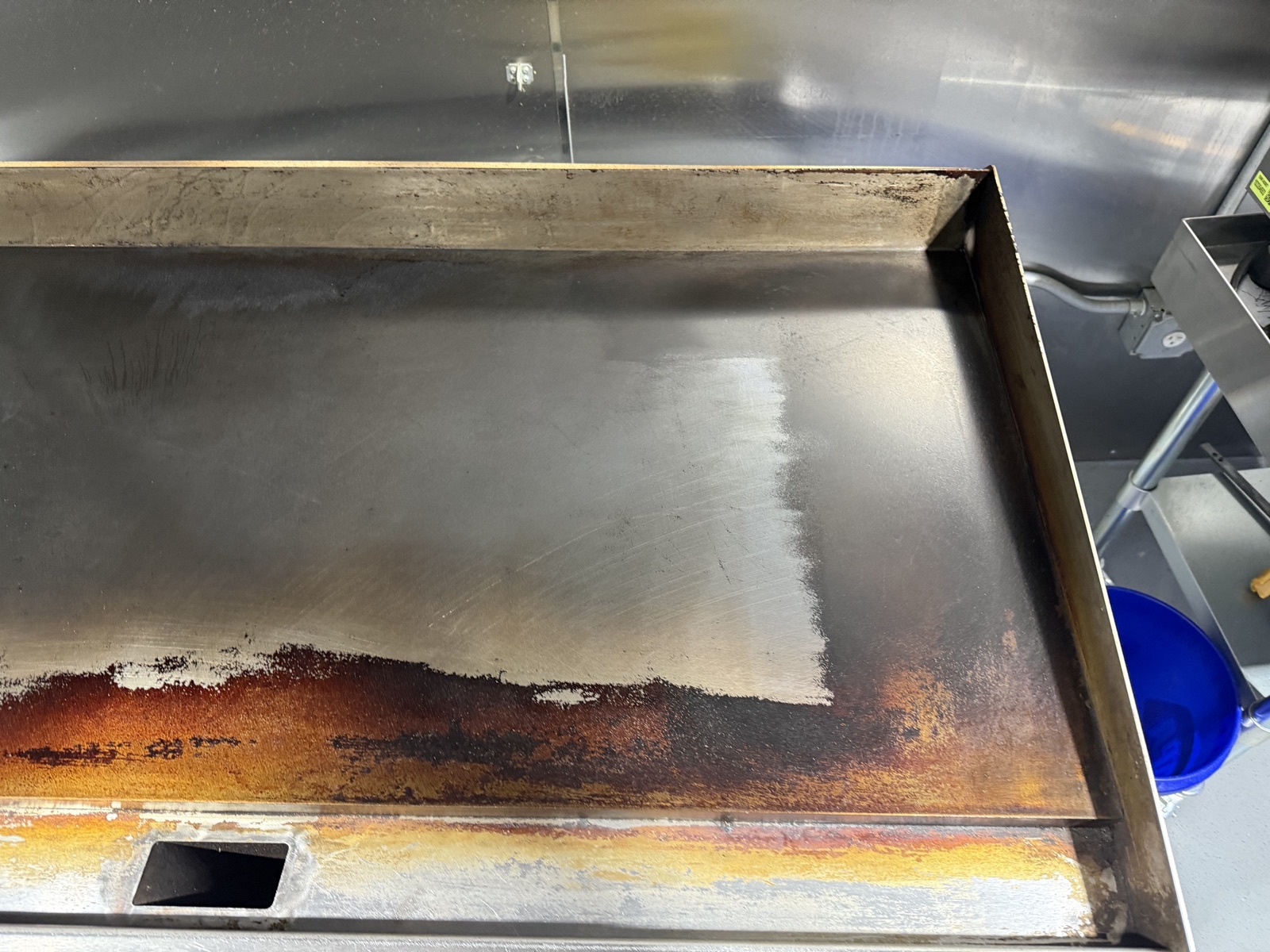 Commercial griddle flat top dry ice blasting mid-clean — bare metal revealed